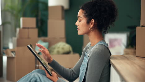 woman using tablet surrounded by moving boxes