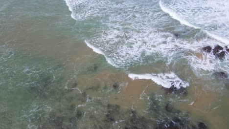 los drones vuelan hacia afloramientos rocosos con olas rompientes en la playa de sawtell cerca del promontorio de bonville en nueva gales del sur, australia