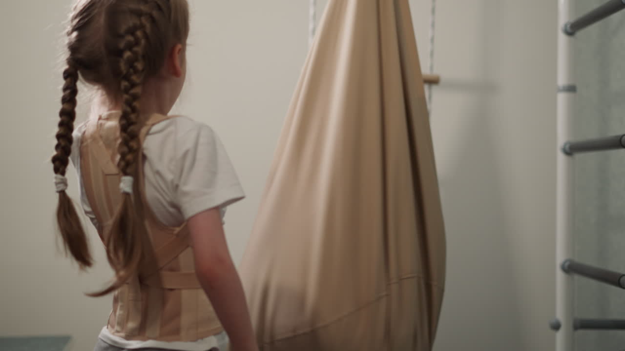 Bambina con infortunio alla schiena gira l'amaca con il fratello.