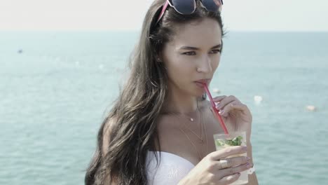 beautiful girl drinks mojito cocktail on the background of the sea