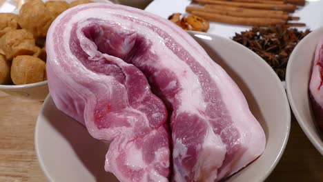 Pork-Belly-in-Ceramic-Bowl-with-Fried-Tofu-in-Background,-Close-Up