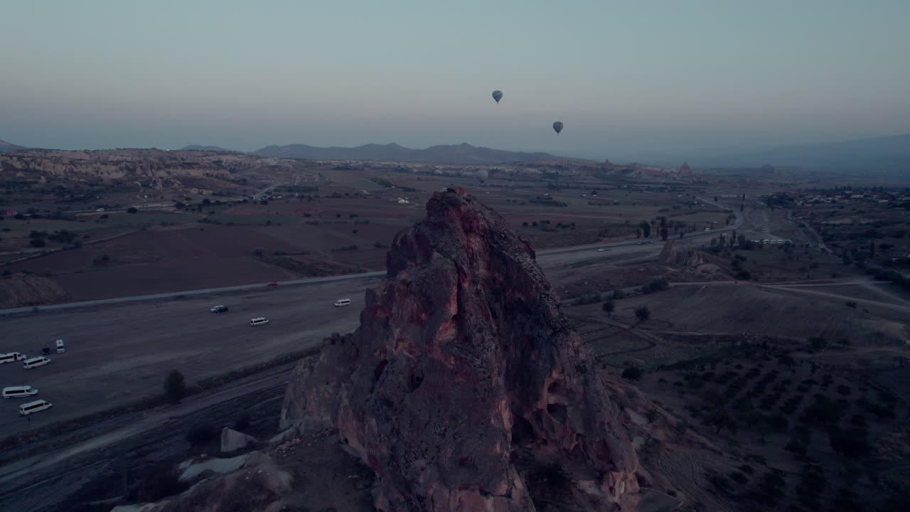 Cappadocia's rocky terrain with hot air balloons at sunrise