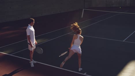 woman and man playing tennis on a sunny day