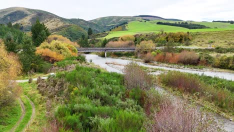 a tranquil river meanders through lush greenery and rolling hills under overcast skies at lake tekapo, new zealand