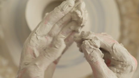 artist cleans his hands of sticky clay after finishing craft work on the throwing wheel