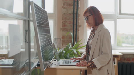 mujer de negocios cargando computadora portátil con panel solar en la oficina