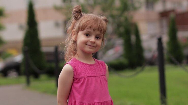 Niña pequeña con el fondo borroso de una calle de la ciudad. Alegría, emociones positivas, sonrisa