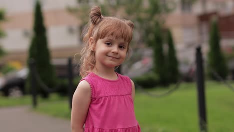 little child girl against the blurred city street background. cheerful, positive emotions, smile