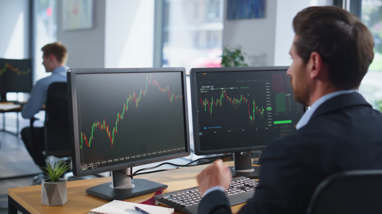 Stock trader looking monitors analyzing currency market charts in office closeup
