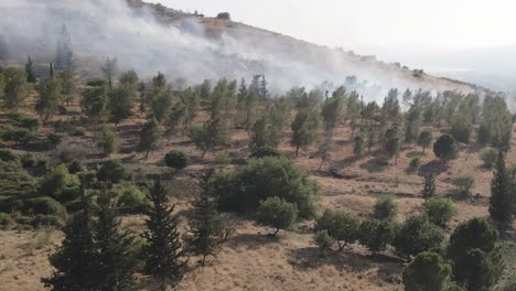 dense smoke blowing across countryside hill from bus accident, drone flyover