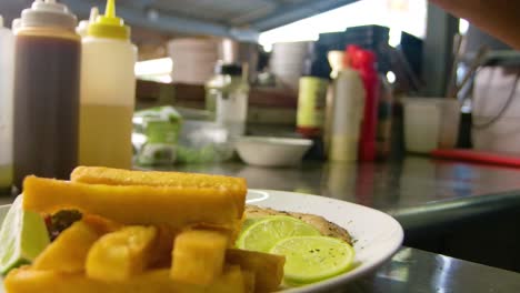 Chef-wearing-black-gloves-dropping-seasoning-on-white-plate-in-kitchen