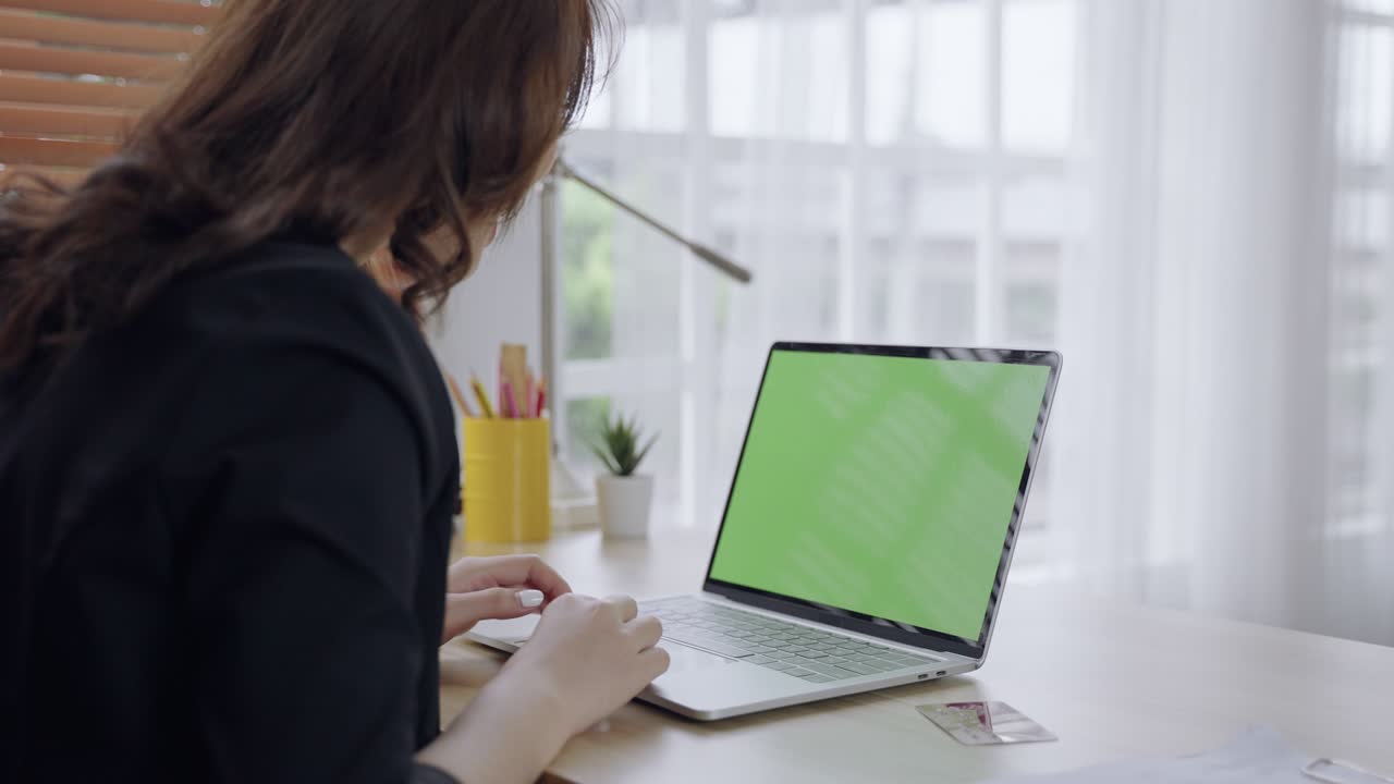 imágenes de pantalla verde de una computadora portátil con una mujer asiática sentada con la espalda.