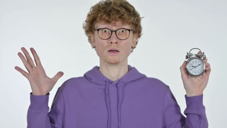 already late, shocked redhead young man holding clock, white background