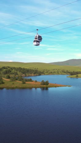 zlatibor, serbia. vertical drone shot of gold gondola cabins above ribnicko lake on sunny summer day