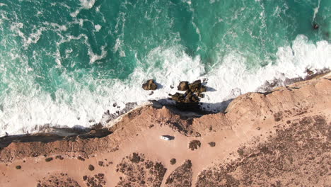 Aerial-top-down-shot-of-camper-van-on-edge-of-steep-cliffs-during-sunny-day---Nullarbor-SA,-Australia