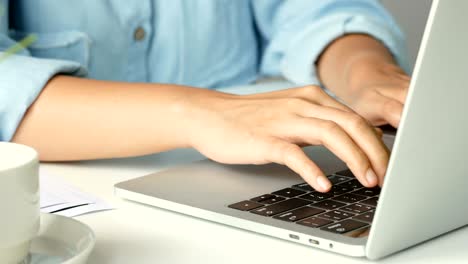 close up hand typing on a keyboard computer laptop at office. one young woman only using computer desktop pc.