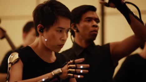 an intense rehearsal of dance performers utilizing advanced technology with motion sensors and unique costumes for a futuristic performance experience