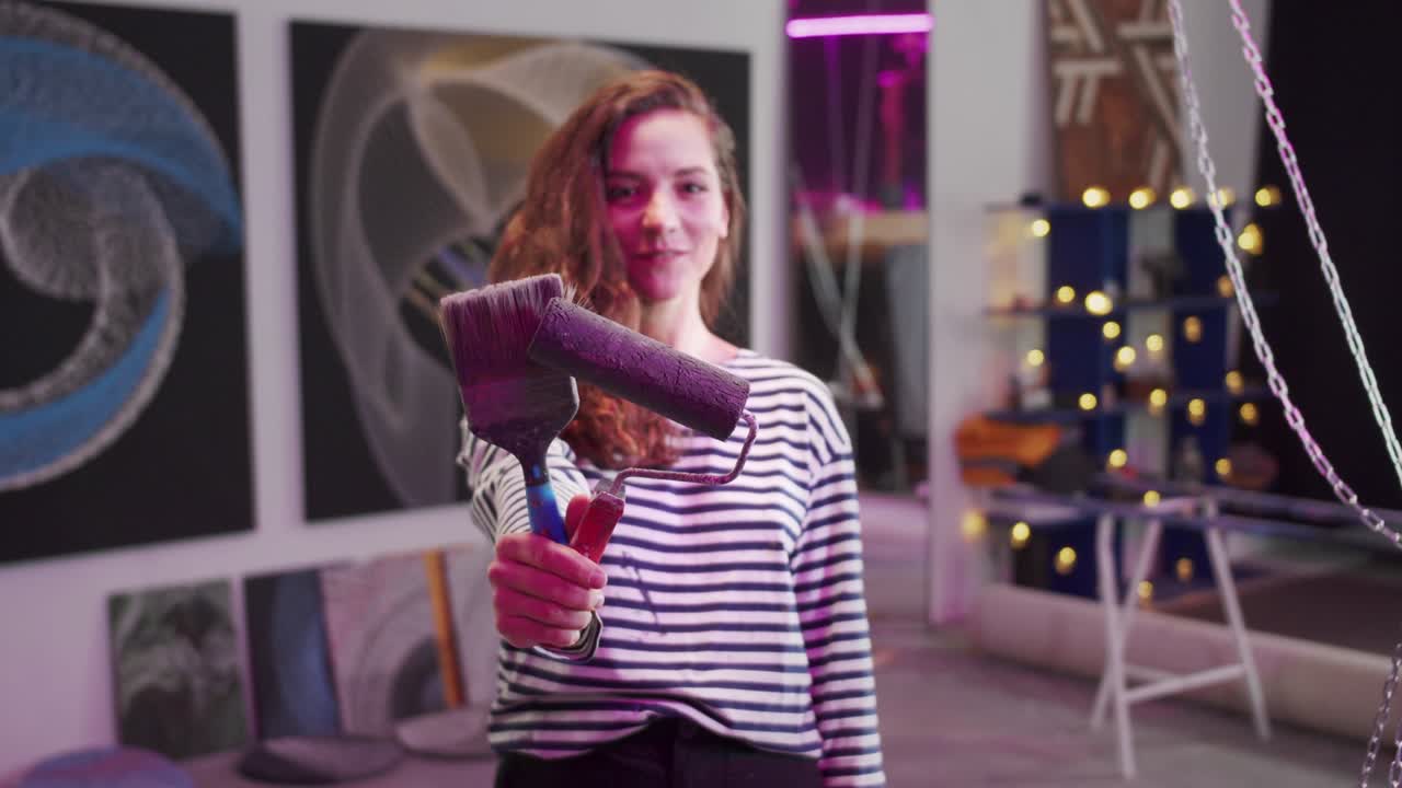 un pintor sonriente está de pie con herramientas y mirando a la cámara