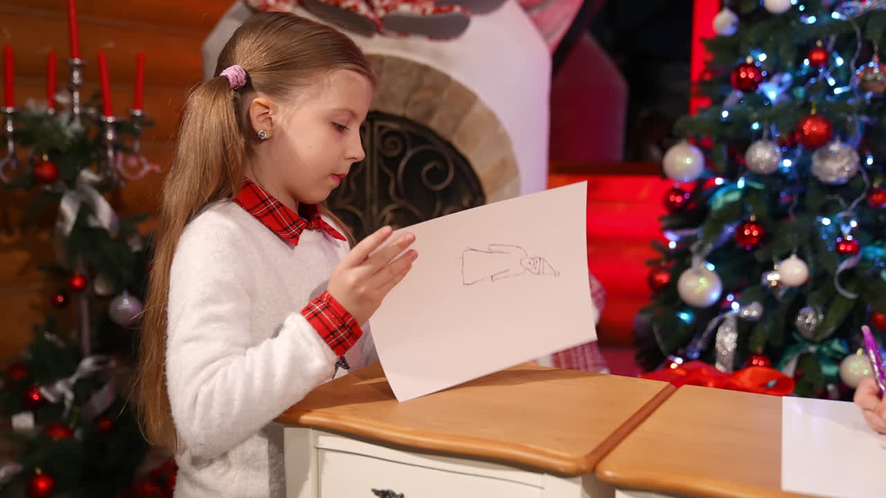 Children painting at Christmas decorated room. Cute little girls sitting on floor and drawing pictures on small desks for Santa. Christmas spirit concept