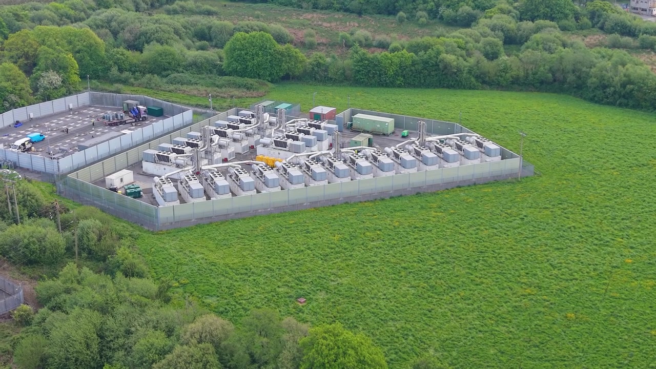 Approaching Aerial of modern gas peaking plant with exhaust stacks, generators, cooling systems. Rapid-response electricity to the grid. Energy infrastructure. BESS Battery under Construction. UK.