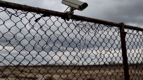 security camera on a rusty chain link fence