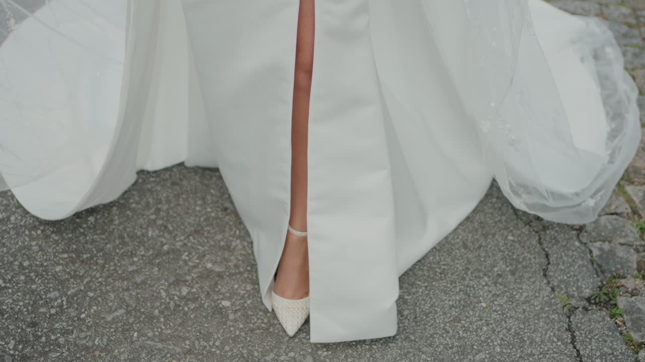 Bride’s leg peeking through a slit in her white wedding gown, showing her white wedding shoe