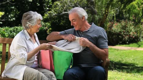 elederly couple looking at clothes after shopping on a bench