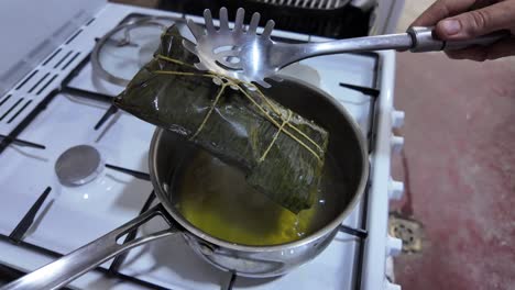 a pot of boiling oil with a kitchen utensil stirring, preparing a traditional hallaca
