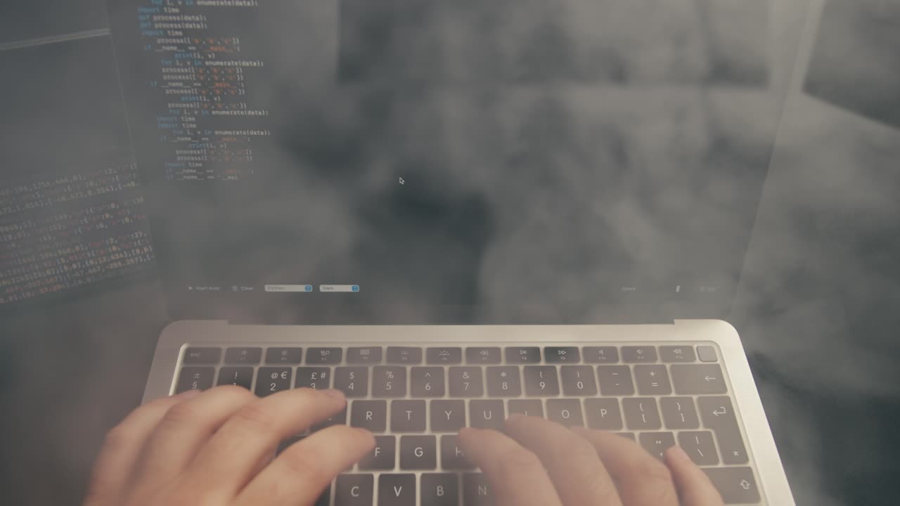 Close-Up of Hands Typing Code on Laptop Keyboard with Smartphone