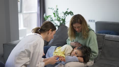 doctor examines little girl checks oxygen level on mom's knees