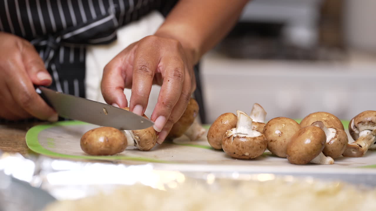 Hands seen chopping off mushroom stems with a sharp chef's knife - slow motion