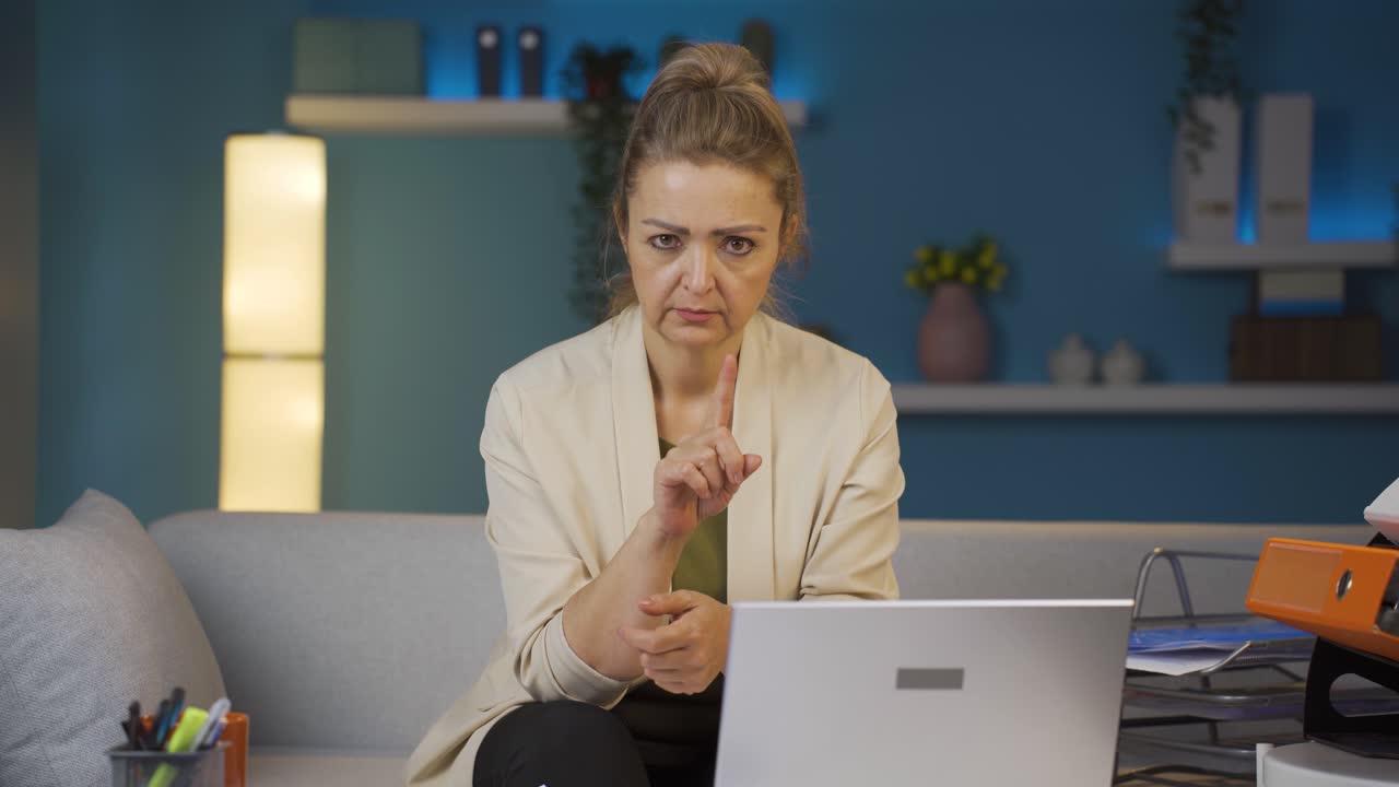 una mujer trabajadora de oficina en casa mirando a la cámara con una severa advertencia enojada.