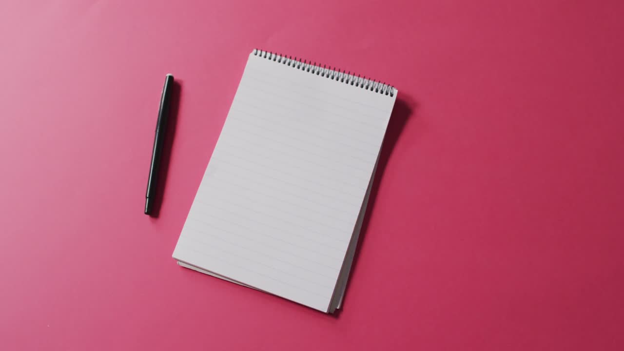 Video of pen and notebook with copy space on pink background