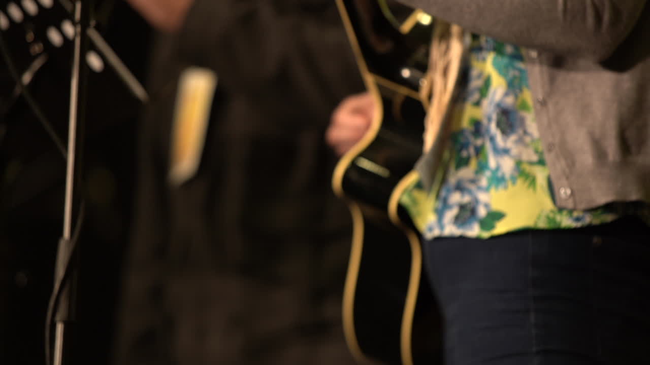 Donna che suona la chitarra durante un servizio di culto in chiesa cristiana, HD, rallentatore, primo piano.