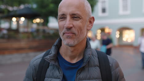 close up portrait of mature attractive caucasian tourist man looking cheerful at camera laughing urban background