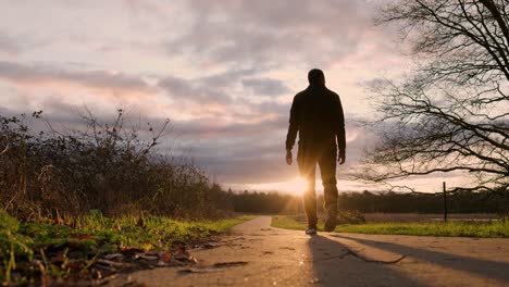 man walking on a path at sunset