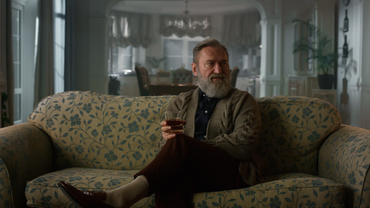 Thoughtful old man thinking while drinking alcoholic drink