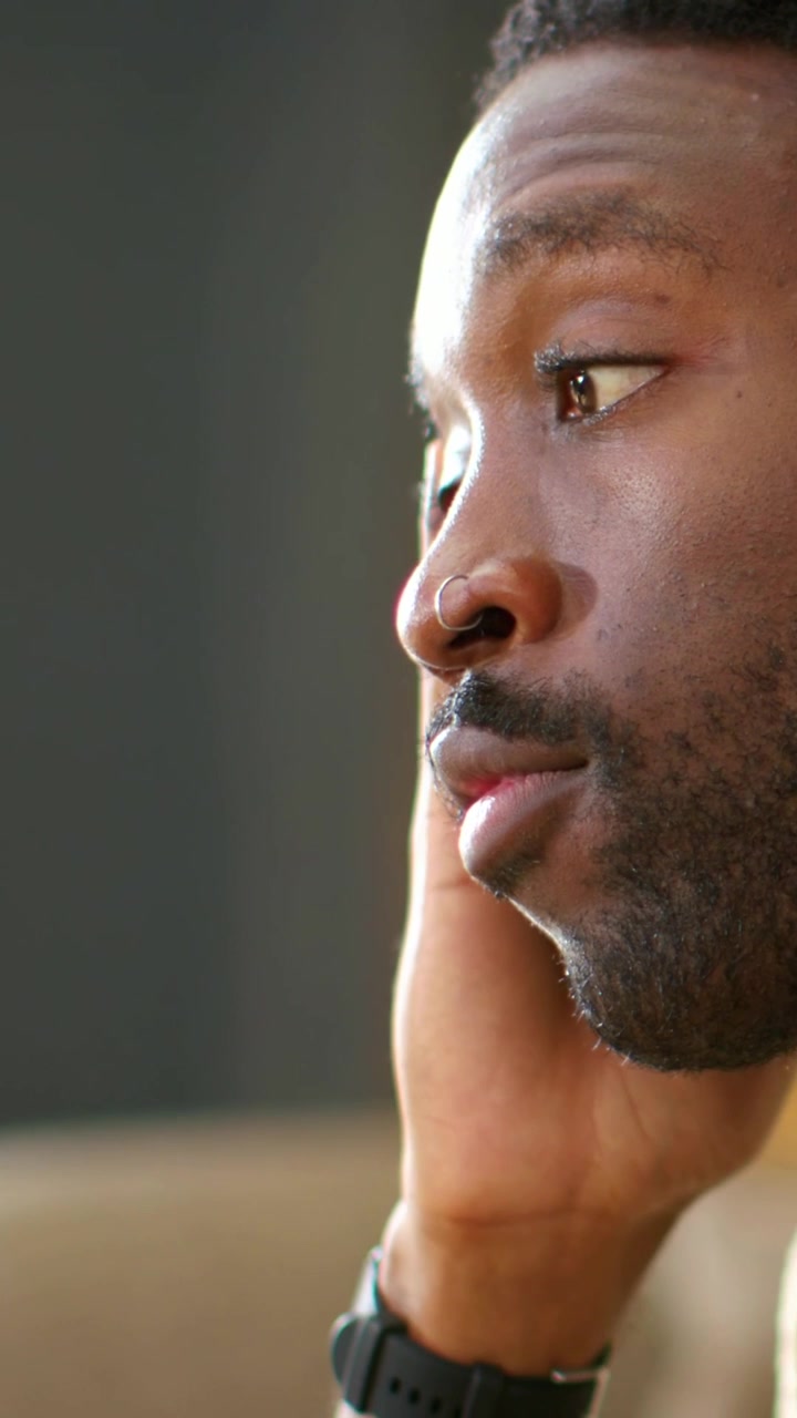 Vertical video: Pressing hand to head, man tired at home, looking right and closing eyes, watch