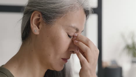 Close-Up-Of-A-Middle-Aged-Woman-With-A-Migraine-Holding-The-Bridge-Of-Her-Nose