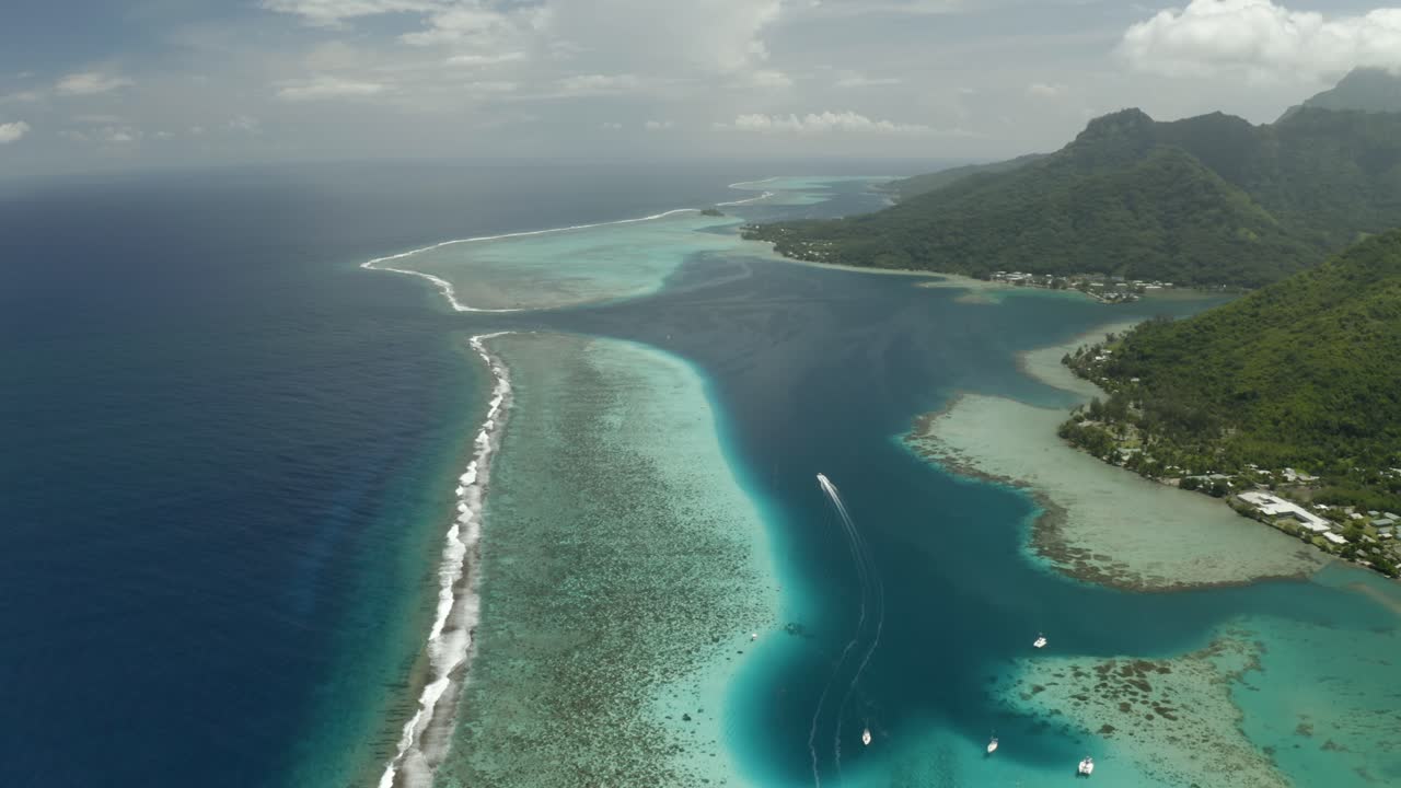 Aerial establishing shot of Mo'orea island coastline and reef barrier in French Polynesia
