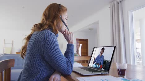 mujer caucásica usando portátil y auriculares de teléfono en videollamada con un colega masculino
