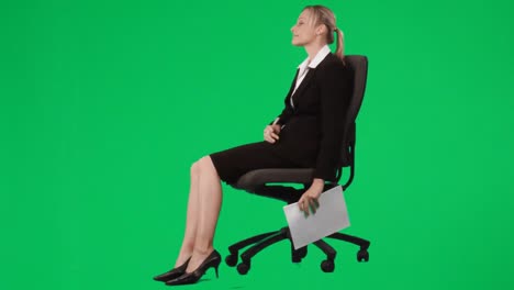 businesswoman sitting on a chair writing notes against green screen