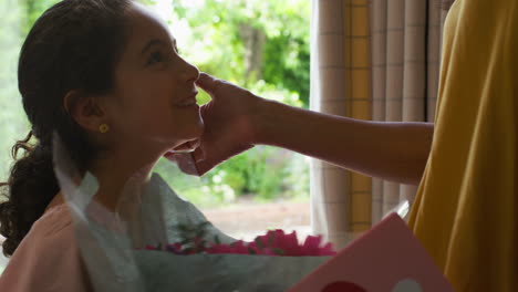 Close-Up-Of-Daughter-Giving-Mother-Bunch-Of-Flowers-And-Homemade-Card-For-Birthday-Or-Mothers-Day-At-Home