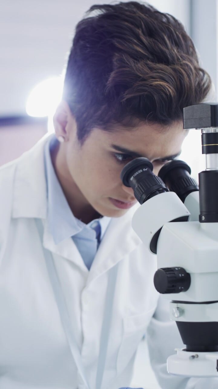 Young Scientist Looking Through Microscope in Laboratory
