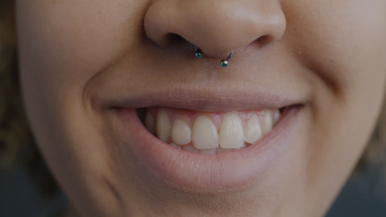 Close-up of a smiling woman with a nose piercing