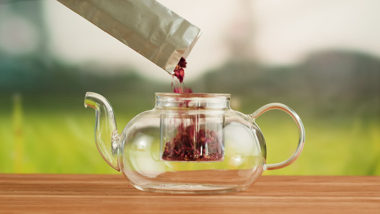 Pouring herbal tea into a clear glass teapot