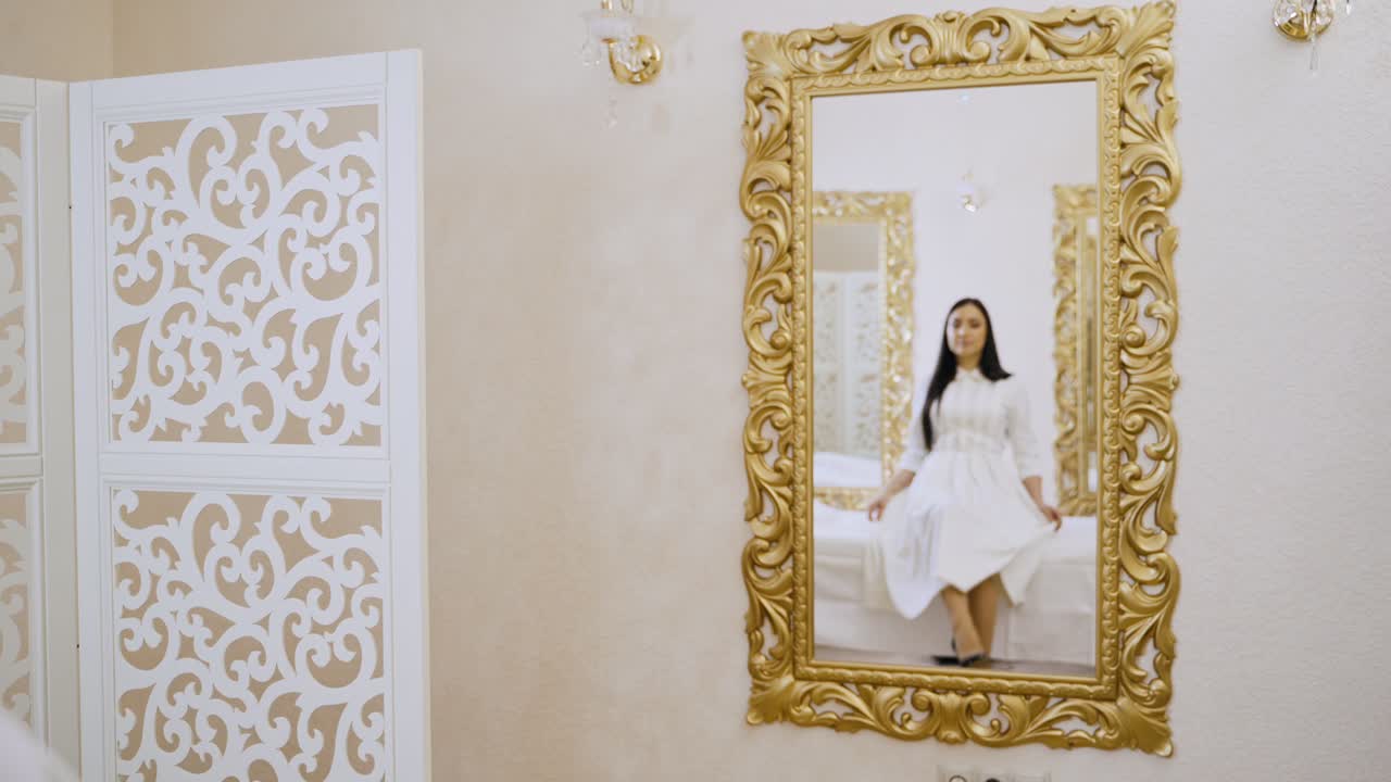 Ragazza che prova un vestito vicino allo specchio in una stanza. Giovane donna attraente in abito che si guarda allo specchio.