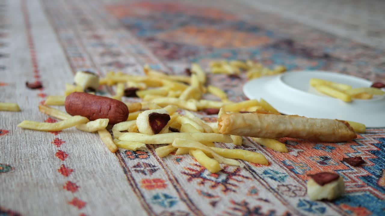 Batatas Fritas, Salsicha e Rolinho Primavera Derramados em uma Toalha de Mesa Estampada