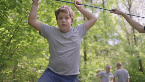 active child fearlessly climbs the ropes between the trees. boy in an adventure park are pass obstacles on the rope road. children camp summer camp