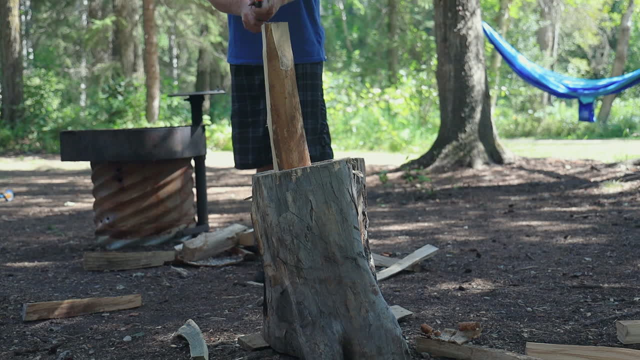 슬로우 모션, 캠핑하는 동안 나무 줄기에 나무를 반으로 자르는 남자